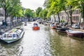 Amsterdam, Netherlands - July 18, 2018: Life on the canals. Barges on the canal and many vehicles on the side streets
