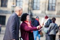 Asian tourists using their cellphones to take pictures at Dam Square in Amsterdam