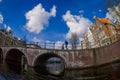 AMSTERDAM, NETHERLANDS, MARCH, 10 2018: Outdoor view of Amsterdam canals with people walking over a bridge and typical