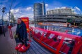 AMSTERDAM, NETHERLANDS, MARCH, 10 2018: Outdoor view of man wearing red huge shoes close to a red excursion boat or Royalty Free Stock Photo