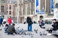 People feeding pigeons in Dam Square at the Old Central district of Amsterdam Royalty Free Stock Photo