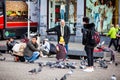 People feeding pigeons in Dam Square at the Old Central district of Amsterdam Royalty Free Stock Photo