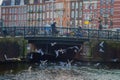 AMSTERDAM, NETHERLANDS, MARCH, 10 2018: People walk on an old stone bridge in the historical part of Amsterdam, with