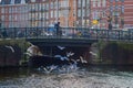 AMSTERDAM, NETHERLANDS, MARCH, 10 2018: People walk on an old stone bridge in the historical part of Amsterdam, with