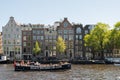 Amsterdam, The Netherlands, May, 2018: Amstel River waterfront on a sunny day with typical houses and boats along the river. Royalty Free Stock Photo