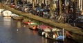 Line of boats in the canal on the background of bicycles and cars on the street in Amsterdam