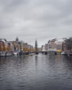 A wide angle view of a canal in Amsterdam on an autumn day, looking towards Montelbaanstoren tower