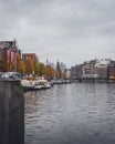 A wide angle view of a canal in Amsterdam on an autumn day, looking towards Montelbaanstoren tower