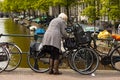 An elderly lady locking her bike on railings