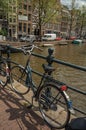 Bridge on canal with iron balustrade, bicycle, old buildings and boats in Amsterdam. Royalty Free Stock Photo