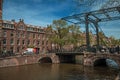 Canal with brick buildings, bascule bridge, bicycles and blue sky in Amsterdam. Royalty Free Stock Photo