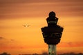 Amsterdam Schiphol International Airport control tower with a plane landing in the background during sunset Royalty Free Stock Photo