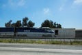 Amtrak train rolling down the rails beside freeway