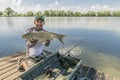 Amur fishing. Fisherman with grass carp fish in hands at lake