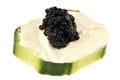Amuse bouche with a slice of cucumber, cream cheese and black lump eggs close-up on a white background