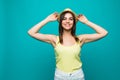 Amused beautiful young woman in white summer clothes, sun hat is looking at camera excited on green background.