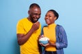 Amused couple watching comedy film on tv and having snack