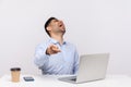 Amused delighted businessman sitting office workplace with laptop on desk, pointing finger to camera and laughing