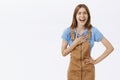 Amused and entertained charming enthusiastic woman in brown overalls bending holding hands on waist holding palm pressed Royalty Free Stock Photo