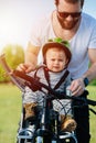 Amused father fitting his funny strict baby boy in a safety baby chair.