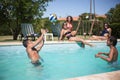 Amused friends playing ball in pool