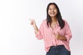 Amused and happy young charismatic malasian female in striped blouse talking and joking pointing left at funny promo Royalty Free Stock Photo