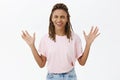 Amused and joyful carefree African-American woman with dreads in pink t-shirt closing eyes raising arms with palms faces