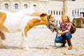 Amused schoolgirl spending her weekend near stable with horse