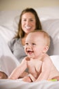 Amused six month old baby with mom in background