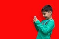 Amused young kid playing games on smartphone - posing at studio