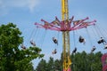 amusement park adults and children stroll against backdrop of swing. people have fun on summer autumn day. teenagers buy