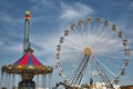 Amusement park carousel and ferris wheel against blue sky. Protaras, Cyprus