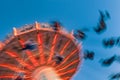 Amusement park motion blurred riders on retro vintage tilting swing against clear blue sky. Royalty Free Stock Photo