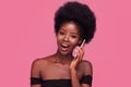 Amusing African American woman chatting with girlfriends on phone or smartphone. Female model with afro hairstyle