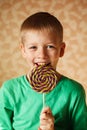 The amusing boy eats big sweet lollipop