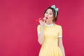 Amusing cute young woman standing and blowing in party whistle