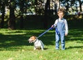 Amusing kid boy copying and teasing dog with sticking out tongue