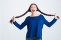 Amusing pretty woman holding her two long braids and shouting