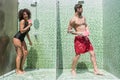 Amusing young couple entertaining simultaneously in near-by shower cubicles Royalty Free Stock Photo