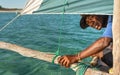 Anakao, Madagascar - May 03, 2019: Unknown Malagasy fisherman looking back under main green sail of his piroga small fishing boat