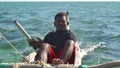 Anakao, Madagascar - May 03, 2019: Unknown Malagasy fisherman sitting on back of his piroga (small fishing boat)