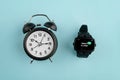 Analog alarm clock against watch