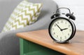 Analog alarm clock on side table in living room, space for text. Royalty Free Stock Photo