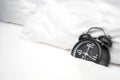 Analog alarm clock is on white bed, Time in the morning with a bright sunshine Royalty Free Stock Photo