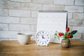 Analog clock with blurred calendar and cup of coffee on wooden table