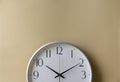 Analog vintage white clock isolated on brown wall background.