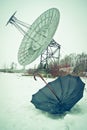 Analogy of black umbrella on the snow with a big dish antenna