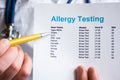 Analysis and testing for allergies photo concept. Doctor points with pen in his hand on result of patient allergy test in foregrou