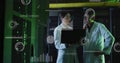 Analyzing data lab coat technicians holding laptop in server room with racks, cables, data overlays Royalty Free Stock Photo