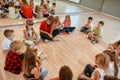 Analyzing mistakes. A group of little dancers sitting on the floor gathered around their female dance teacher and